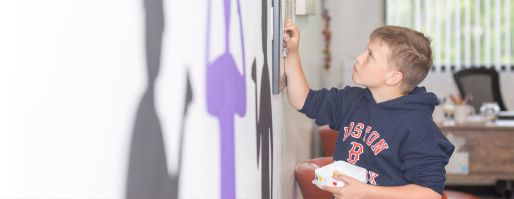 Boy at The Sycamore School painting a mural