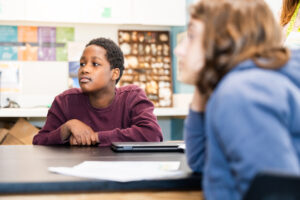 Student sits at a table listening intently to the lesson. 