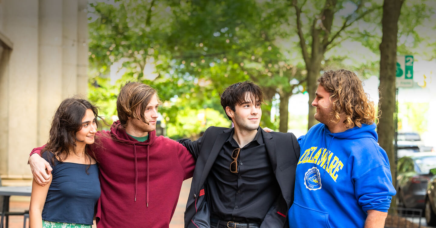 Smiling Sycamore School graduates stand outside with their arms around each other.