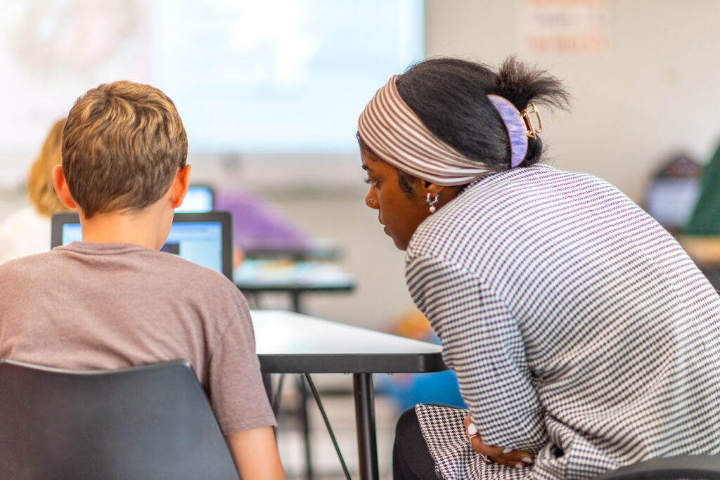Teacher assists their student on an assignment in the classroom.