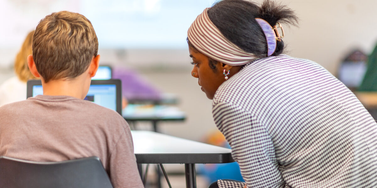 Teacher assists their student on an assignment in the classroom.